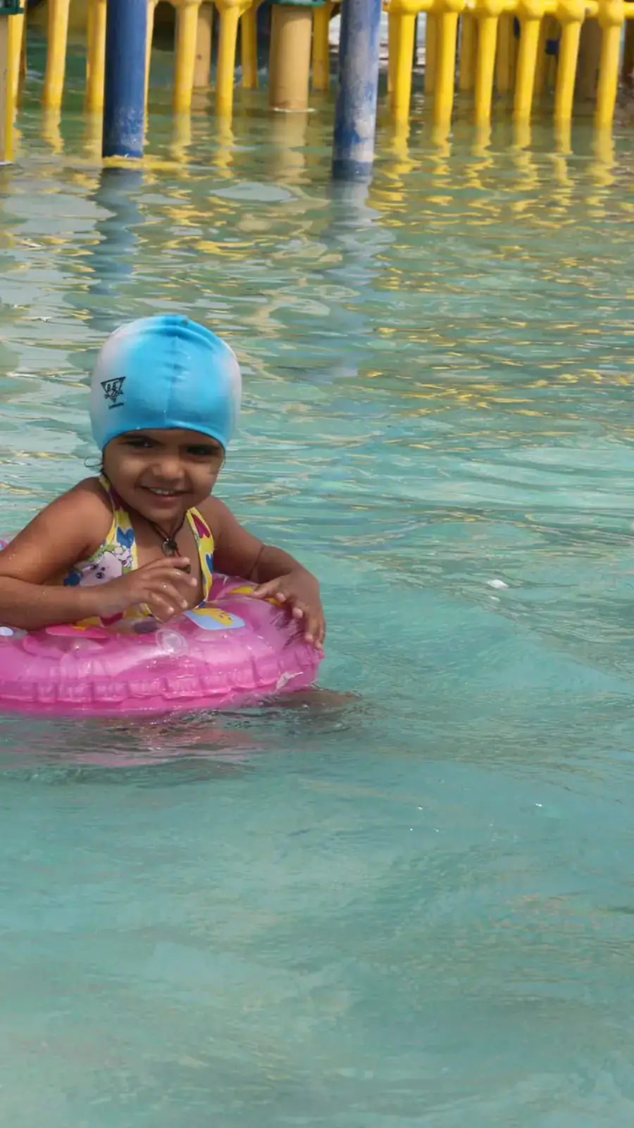 A kid mid-laugh in the water, hair plastered down