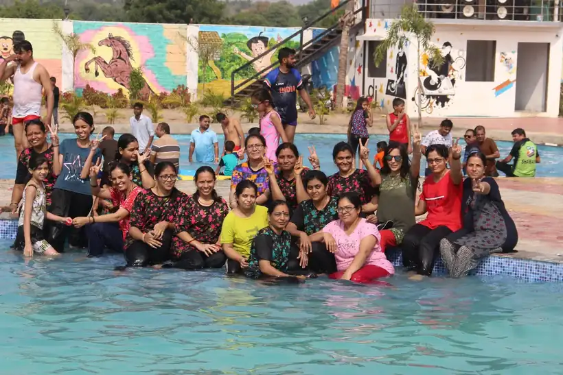 A big group of members and families packed into the main pool, waving